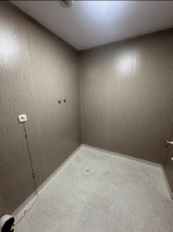 Aménagement salle de douche PMR sécurisée et moderne Cabine de douche PMR vide, parois bois, drain central et bouton d'appel d'urgence avec cordon rouge.